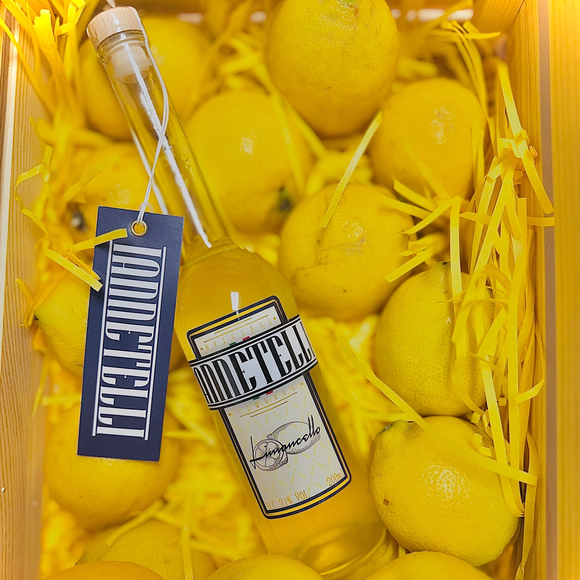 Elegant Iannetelli Limoncello bottle placed with ripe lemons and decorative yellow straw packaging